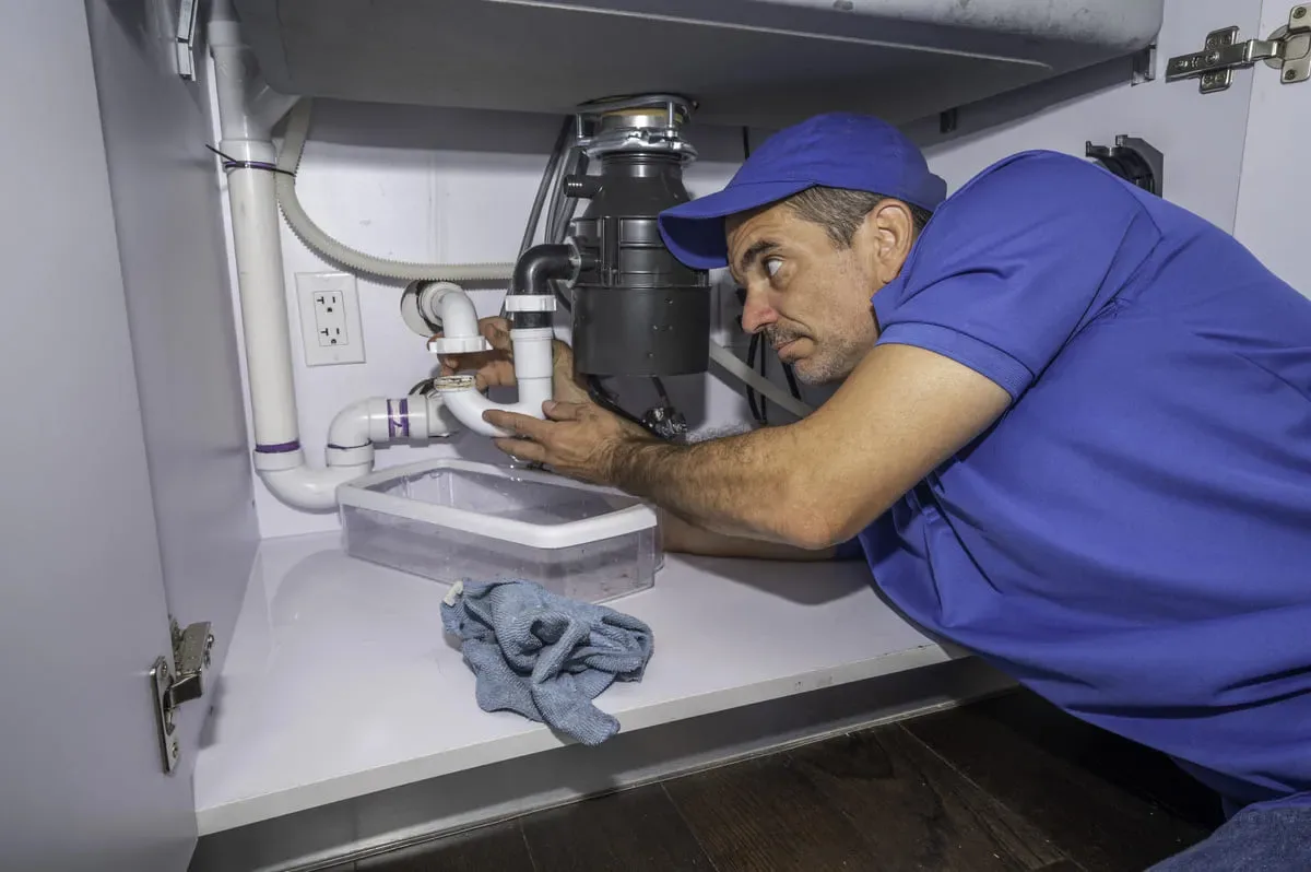 Plumber performing drain cleaning under sink in Halton Hills
