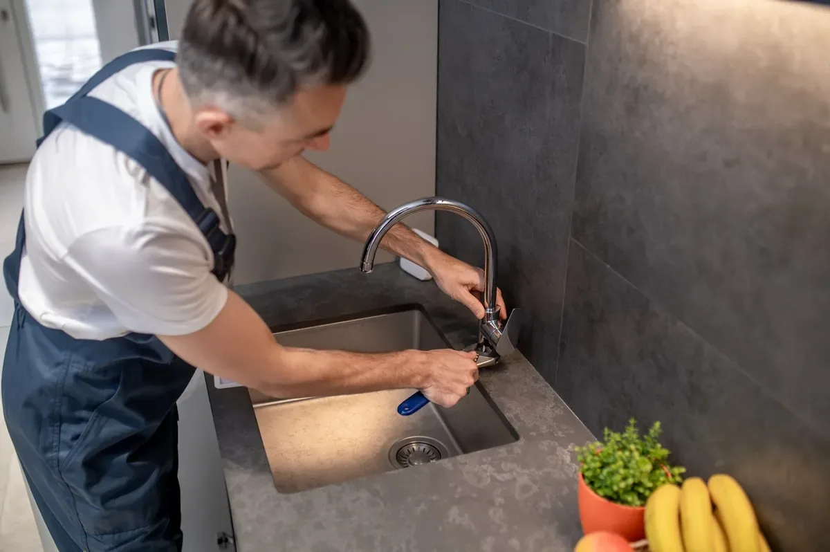 Plumber repairing kitchen faucet near Halton Hills